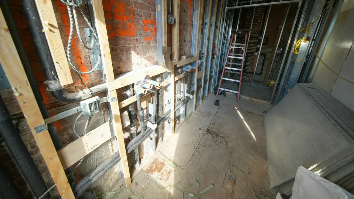 A gutted room with exposed framing, brick and pipes during renovation - Leak Detection in Cape Girardeau